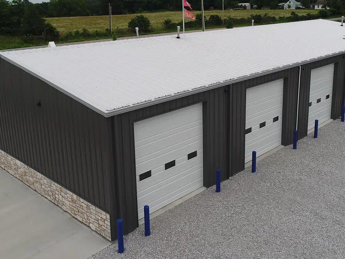 Steel self-storage building with dark gray walls, stone wainscot and a row of white overhead doors